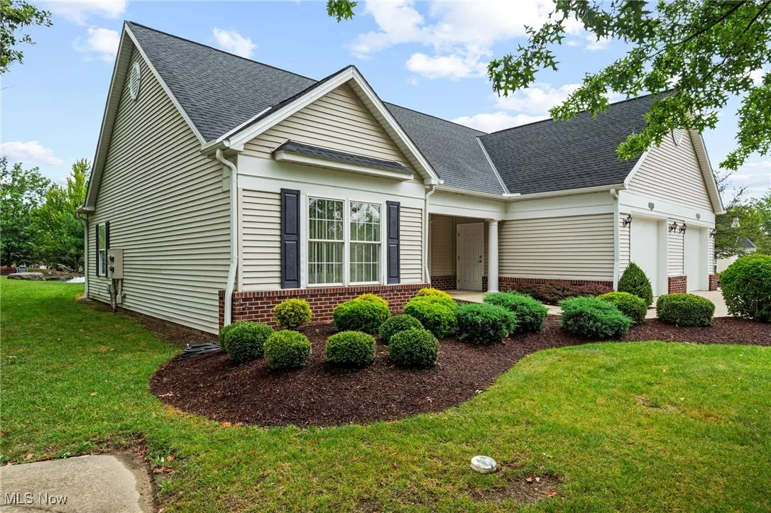 View of front of property featuring a front lawn, brick siding, a shingled roof, and an attached garage