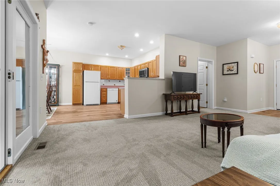 Living room with recessed lighting, light colored carpet, and light wood-style flooring