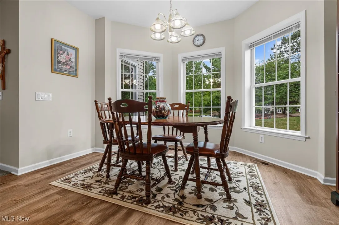 Dining room with healthy amount of natural light, a chandelier, and light wood-style flooring
