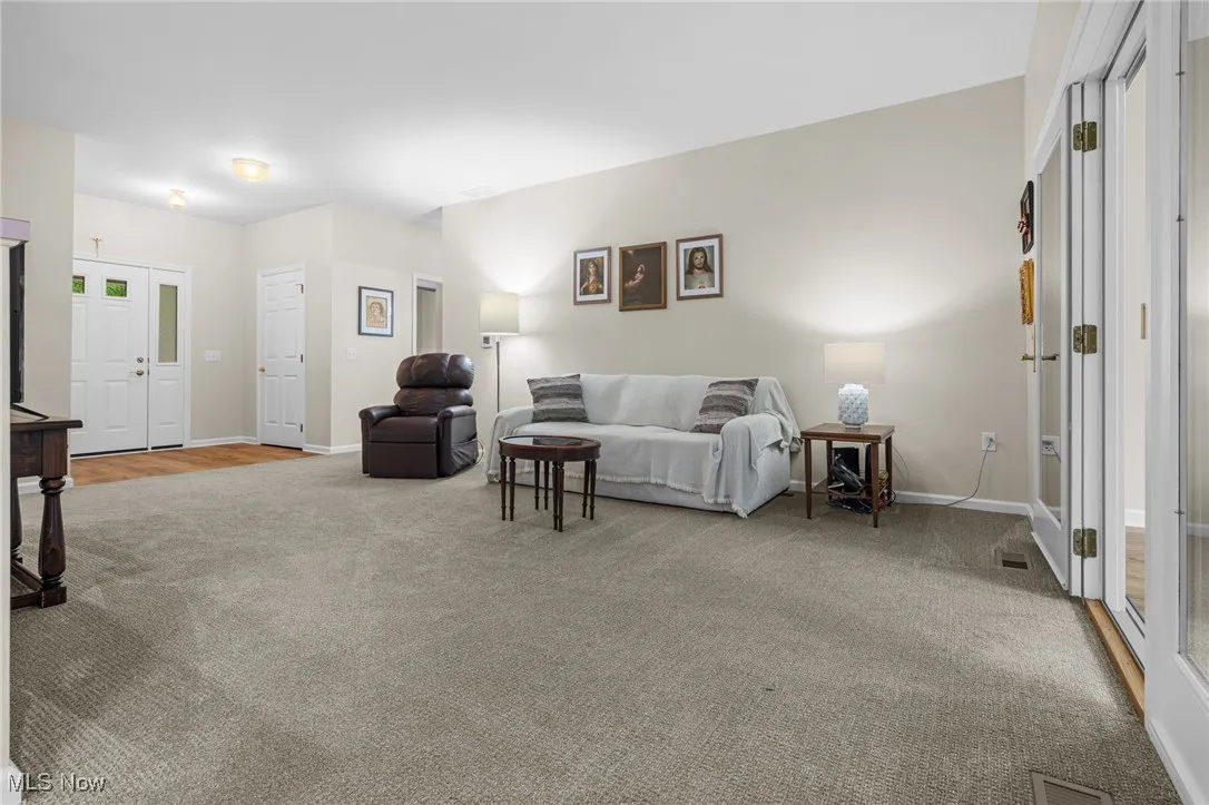 Living area featuring light colored carpet and baseboards