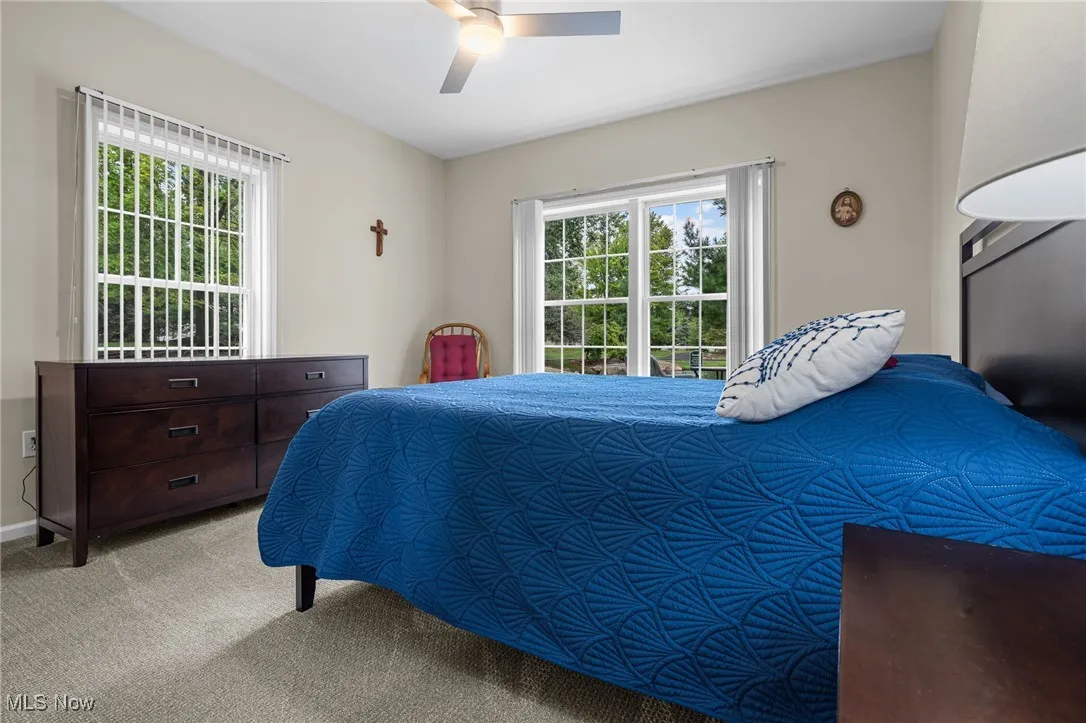 Carpeted bedroom with ceiling fan and baseboards