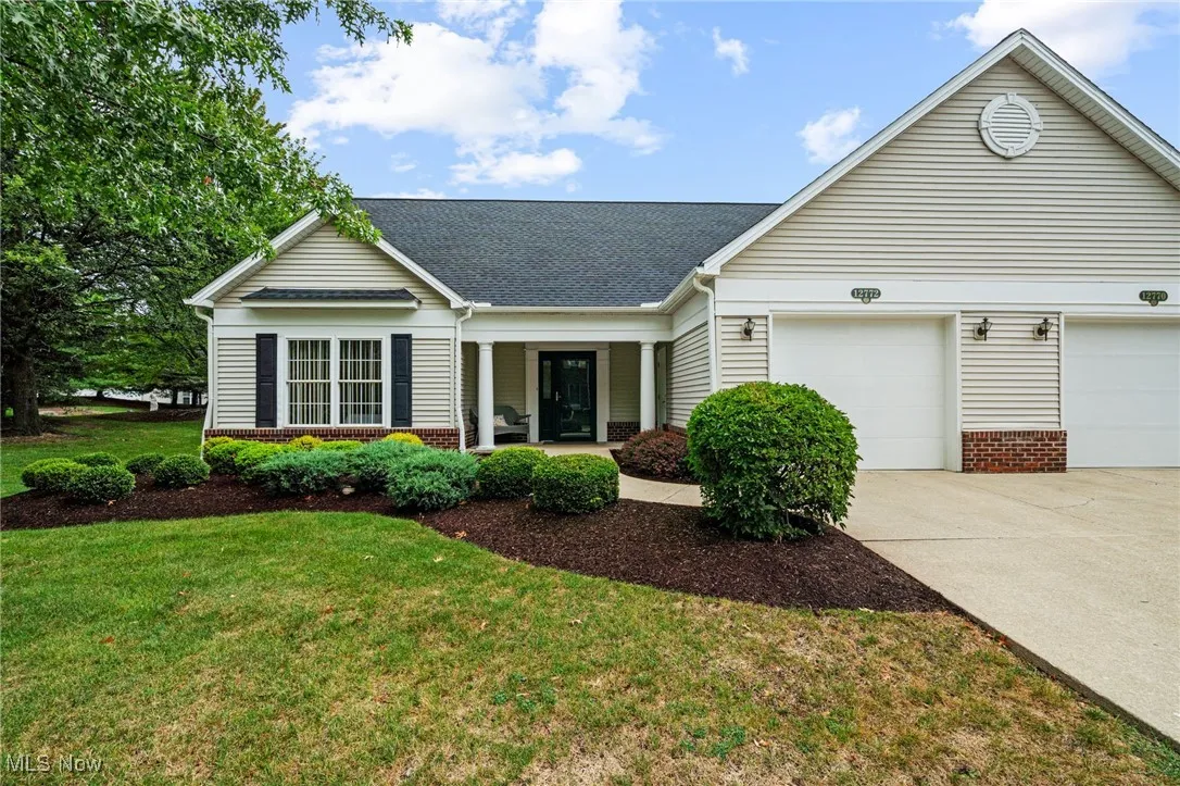View of front of house with a garage, brick siding, covered porch, and concrete driveway
