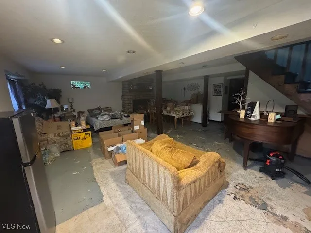 Finished basement featuring freestanding refrigerator, stairway, a fireplace, and recessed lighting