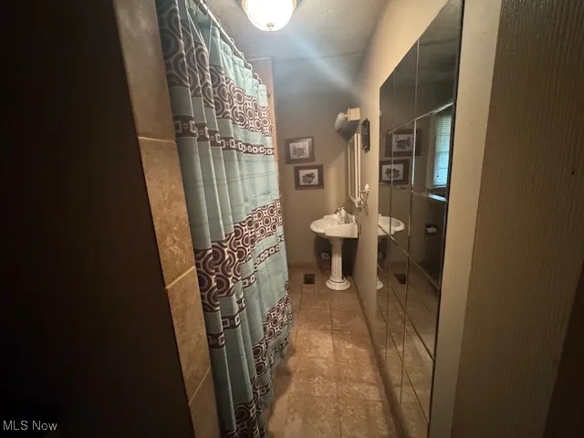 Bathroom featuring light tile patterned flooring and a shower with curtain