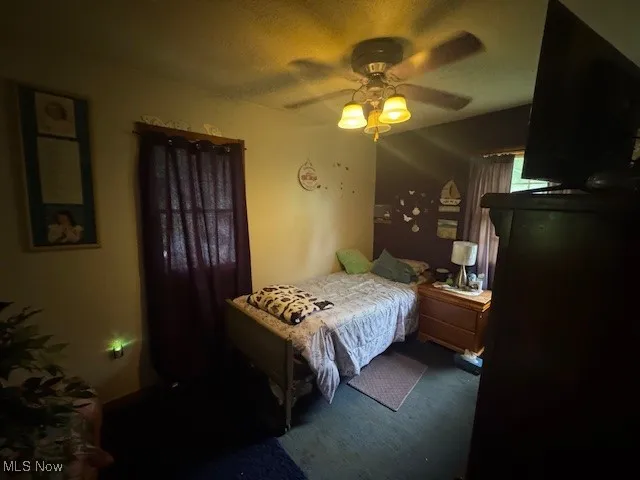 Bedroom featuring ceiling fan, carpet floors, and a textured ceiling