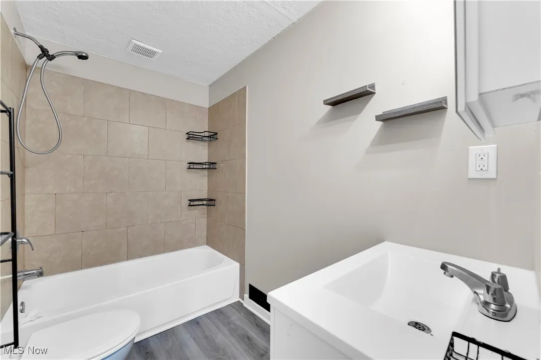 Bathroom featuring bathing tub / shower combination, a textured ceiling, wood finished floors, and vanity