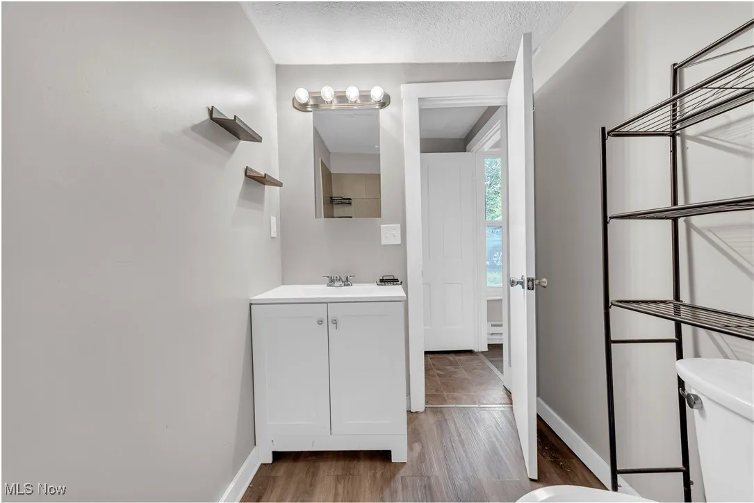 Half bathroom featuring vanity, a textured ceiling, and dark wood-type flooring
