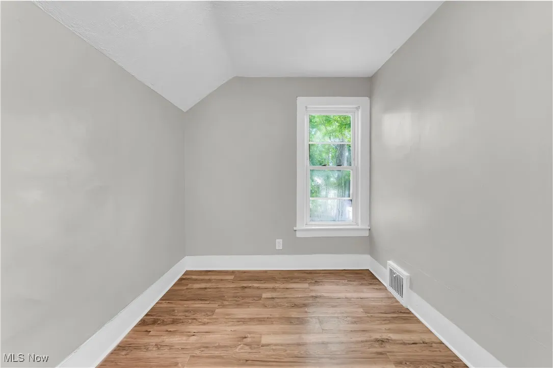Bonus room with light wood-type flooring, vaulted ceiling, and a textured ceiling