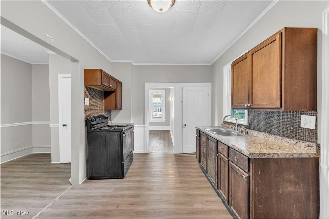 Kitchen with decorative backsplash, electric range, light wood-style flooring, plenty of natural light, and crown molding