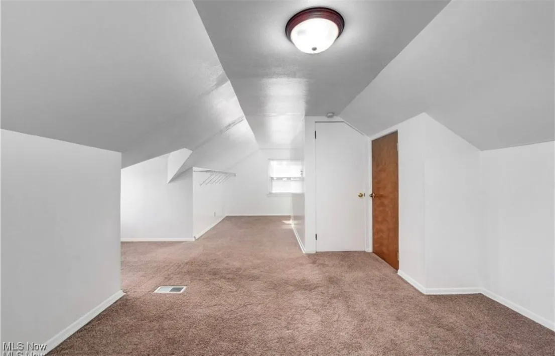 Additional living space with lofted ceiling and light colored carpet