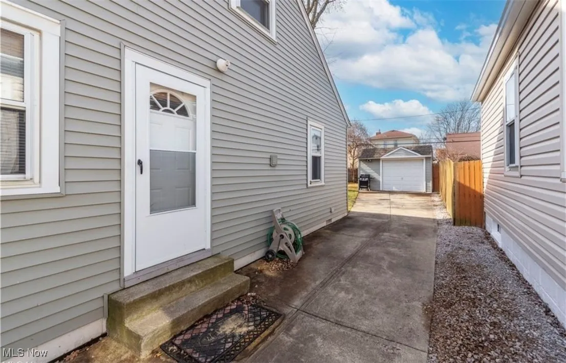 View of property exterior featuring concrete driveway, a garage, and an outdoor structure