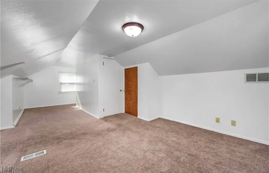 Bonus room with carpet flooring and vaulted ceiling