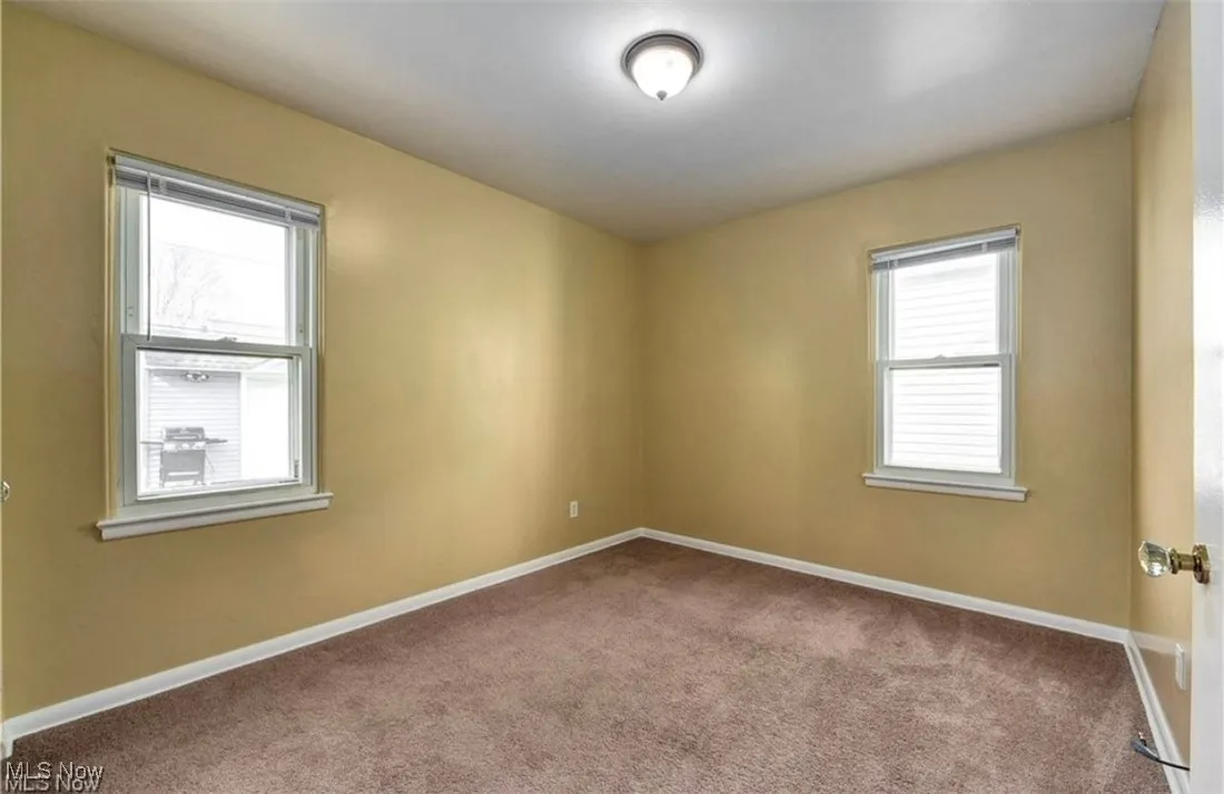 Carpeted spare room featuring baseboards