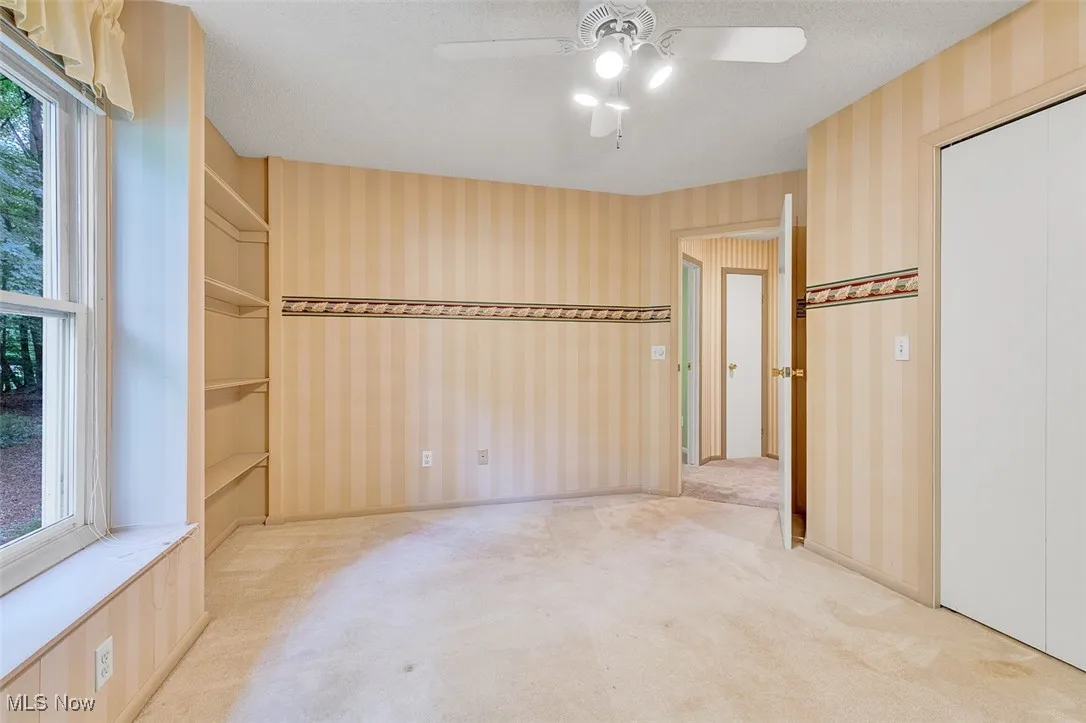 Unfurnished bedroom featuring carpet, ceiling fan, a textured ceiling, and wallpapered walls