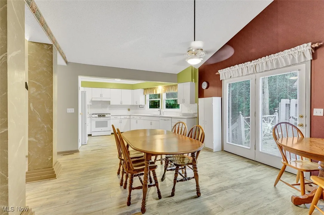 Dining area with lofted ceiling, light wood-style flooring, and a ceiling fan