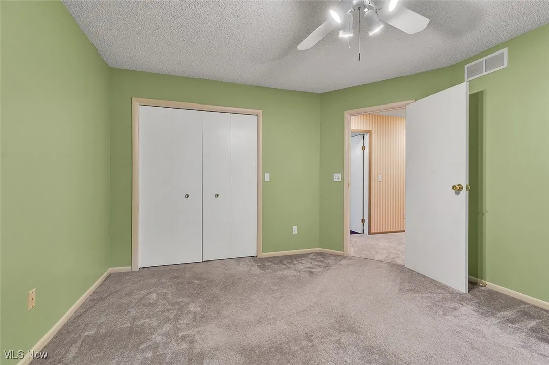 Unfurnished bedroom featuring a textured ceiling, carpet floors, a closet, and ceiling fan