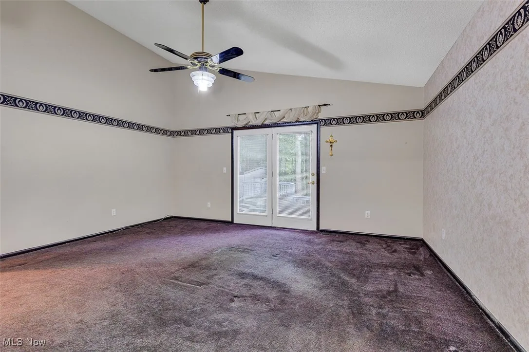 Carpeted spare room with high vaulted ceiling and a ceiling fan