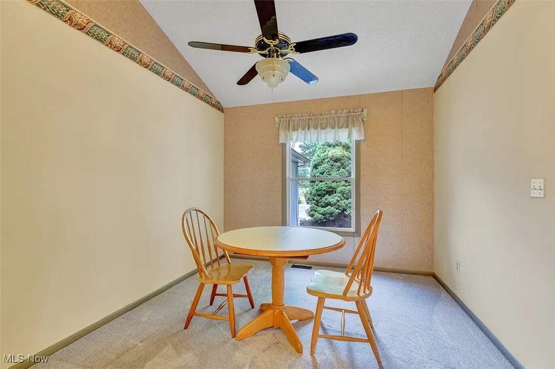 Dining space featuring lofted ceiling, carpet, a ceiling fan, and a textured ceiling