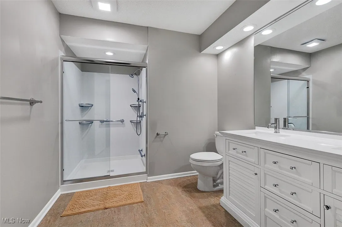 Bathroom with double vanity, a shower stall, and recessed lighting