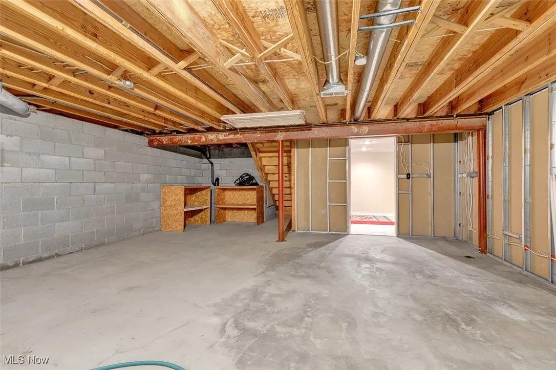 Unfinished basement with concrete block wall and stairs