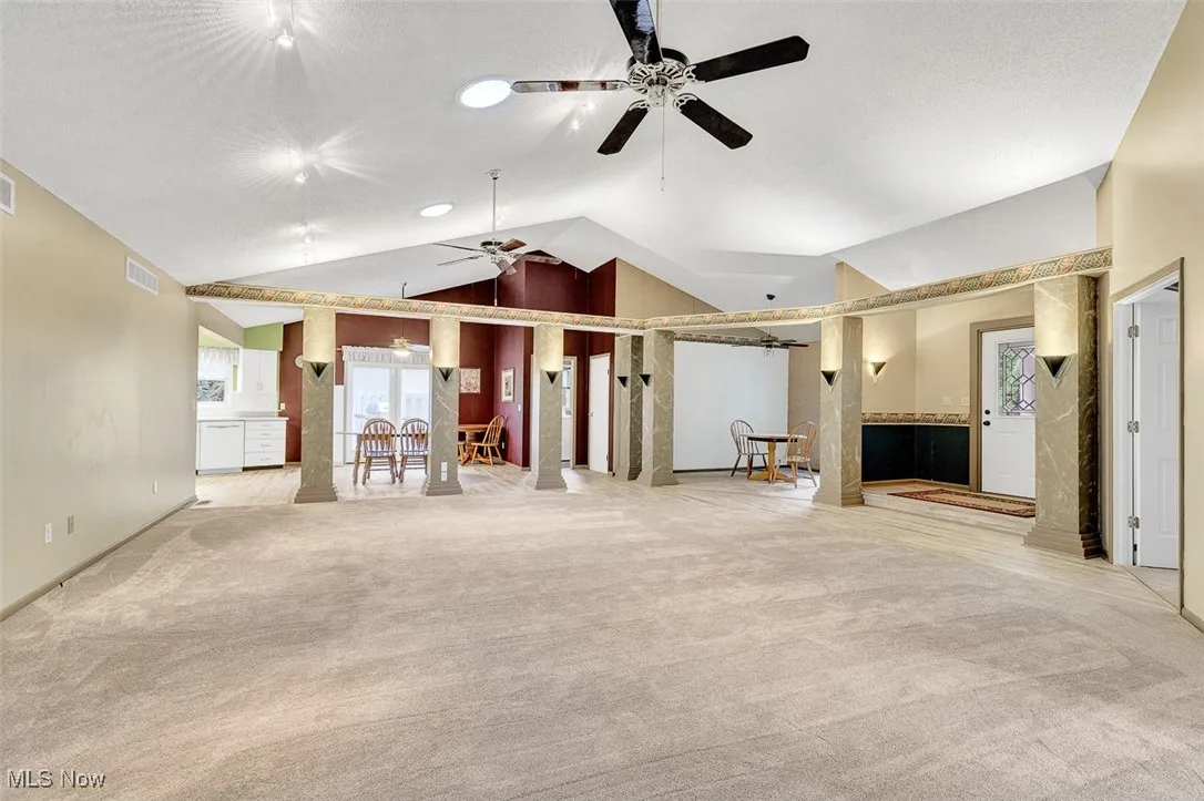 Unfurnished living room with lofted ceiling, light carpet, and a ceiling fan