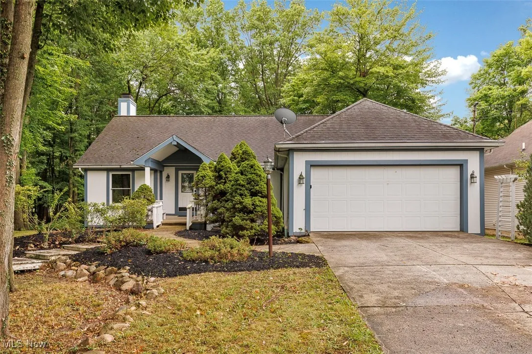 Ranch-style house with an attached garage, concrete driveway, a chimney, and a shingled roof