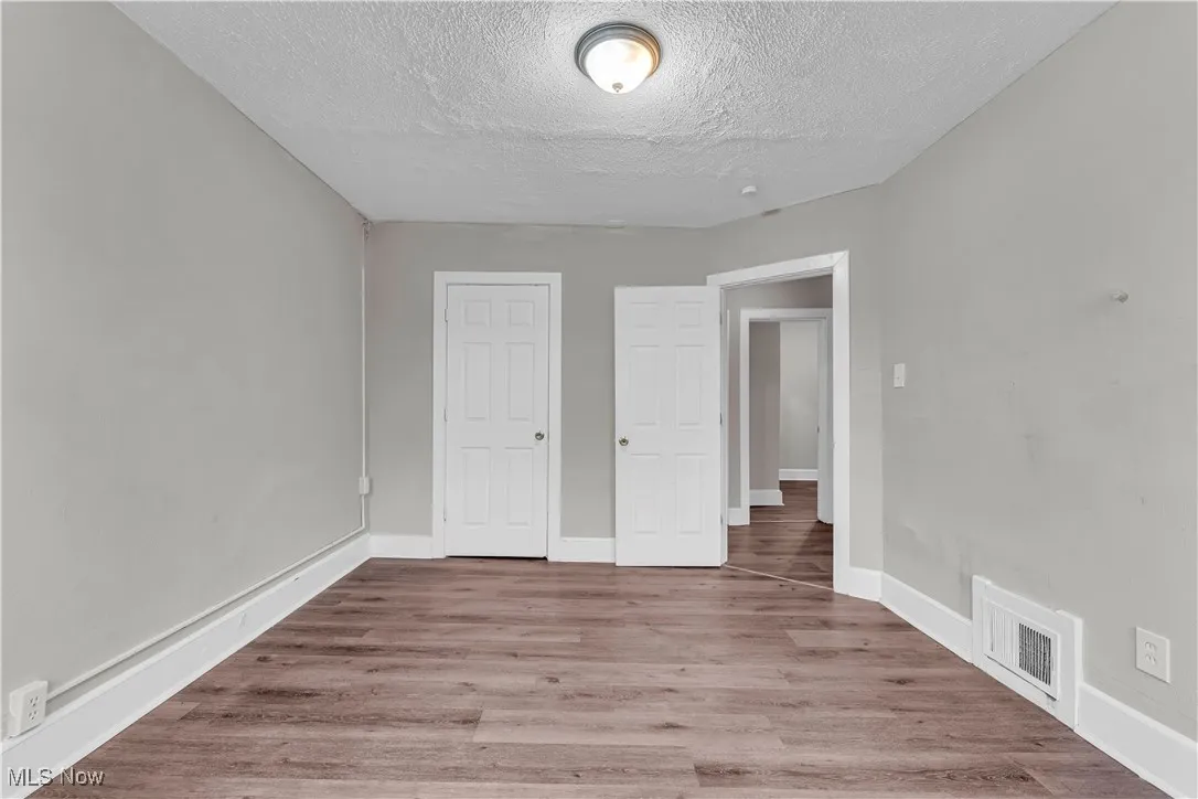 Unfurnished bedroom with wood finished floors, a textured ceiling, and a closet