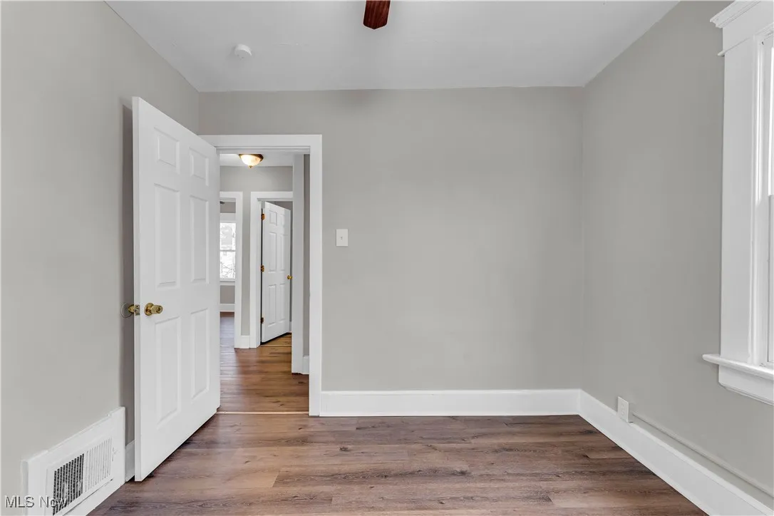 Spare room featuring dark wood-type flooring and a ceiling fan