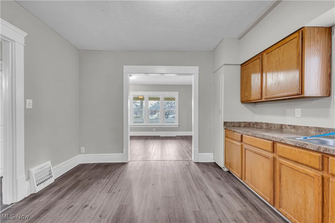 Kitchen featuring light wood-type flooring, a textured ceiling, brown cabinets, and light countertops
