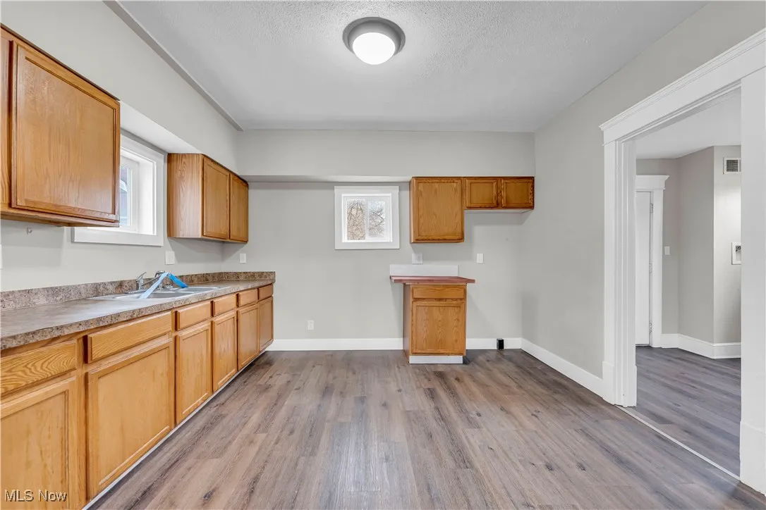 Kitchen with light wood finished floors, light countertops, a textured ceiling, and brown cabinetry