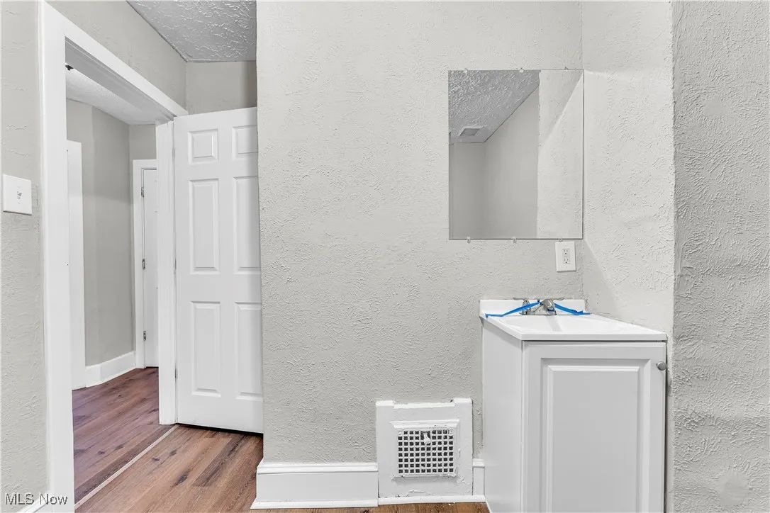 Bathroom with a textured wall, vanity, wood finished floors, and a textured ceiling