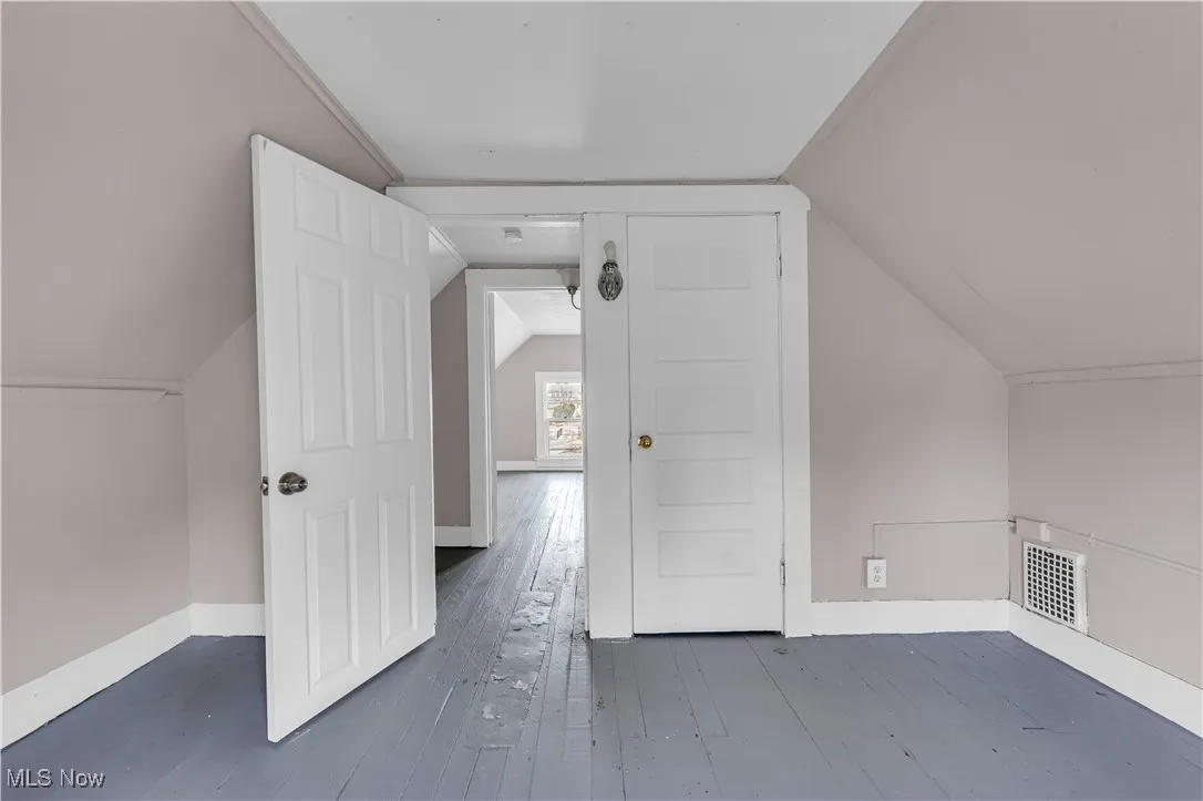 Bonus room with vaulted ceiling and dark wood-style flooring