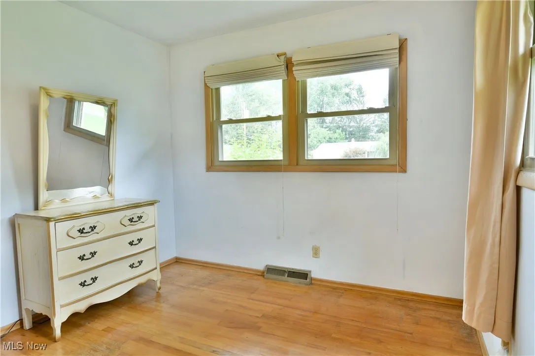 Bedroom with light wood-style floors and multiple windows