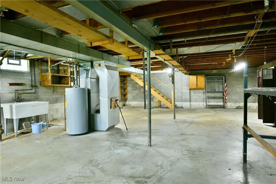 Below grade area with water heater, heating unit, and stairs