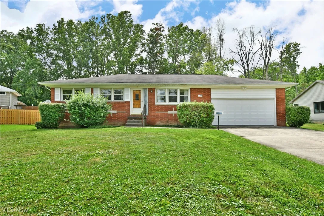 Single story home featuring an attached garage, concrete driveway, brick siding, and entry steps