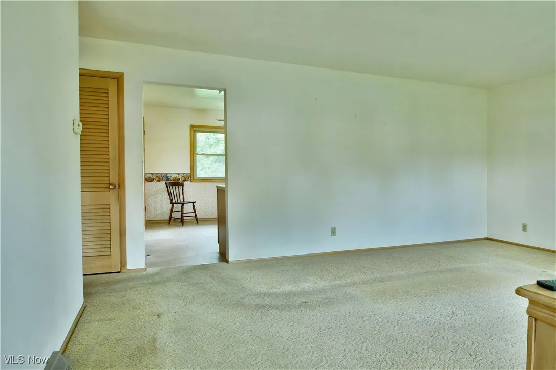 Spare room featuring light carpet and baseboards
