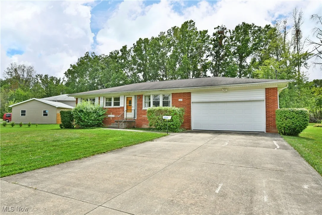 Single story home with brick siding, a garage, concrete driveway, and a front yard