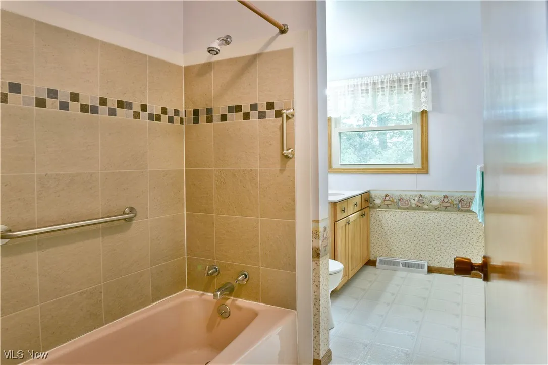 Full bathroom featuring vanity,  shower combination, and wainscoting