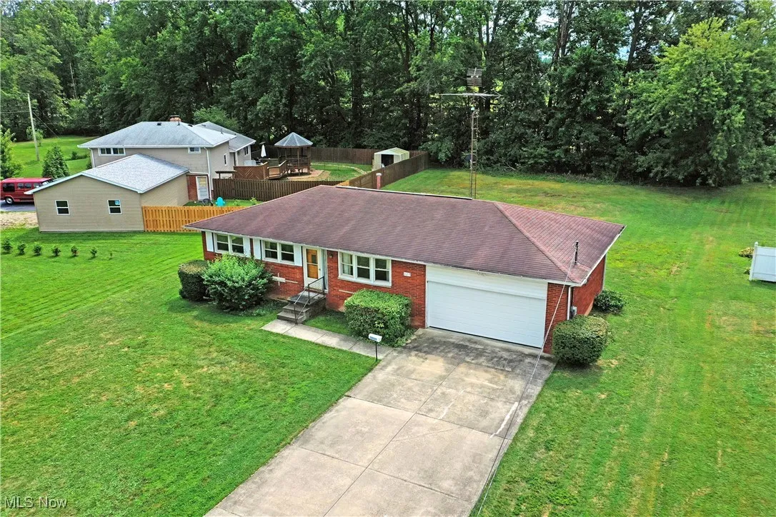 Ranch-style house featuring driveway, a garage, a front lawn, and brick siding