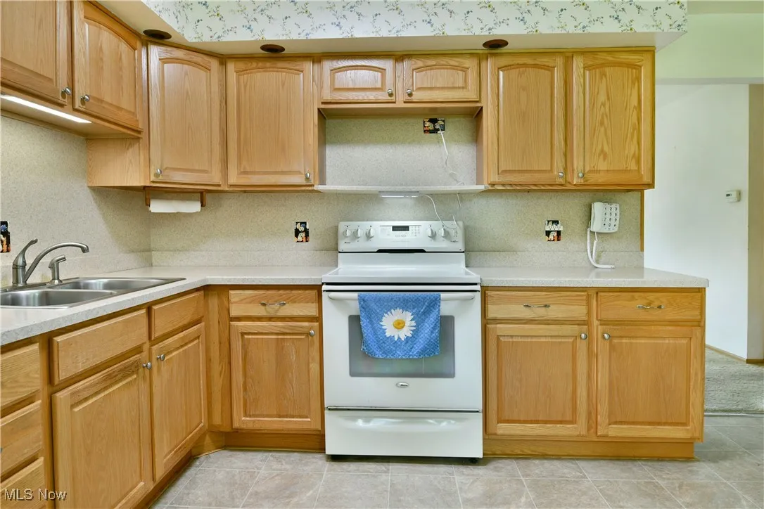 Kitchen featuring white range with electric cooktop, tasteful backsplash, and light tile patterned floors