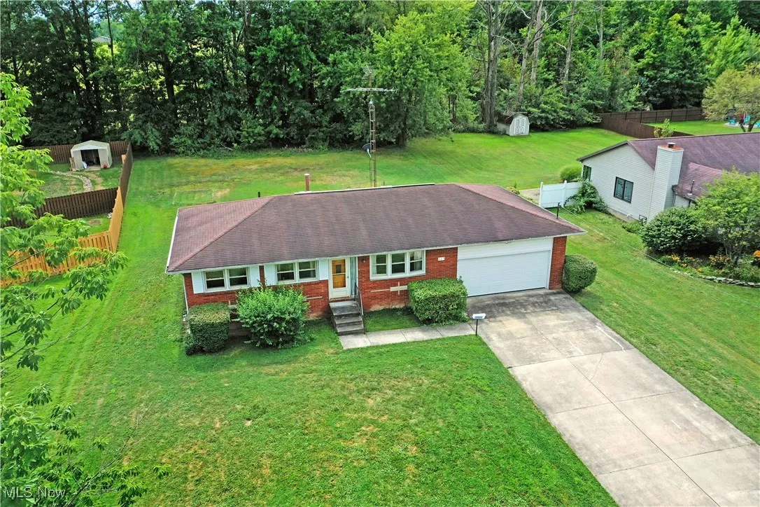 View of front of property with brick siding, driveway, a front lawn, and an attached garage