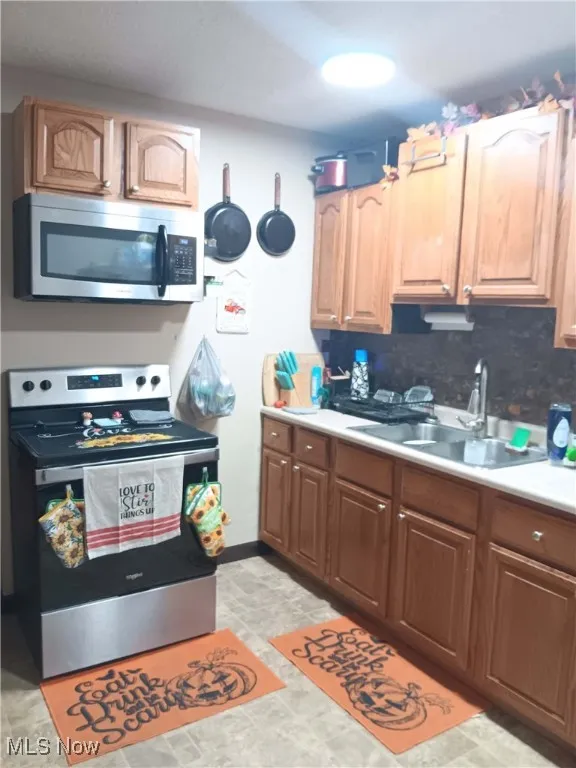 Kitchen with stainless steel appliances, light countertops, and decorative backsplash