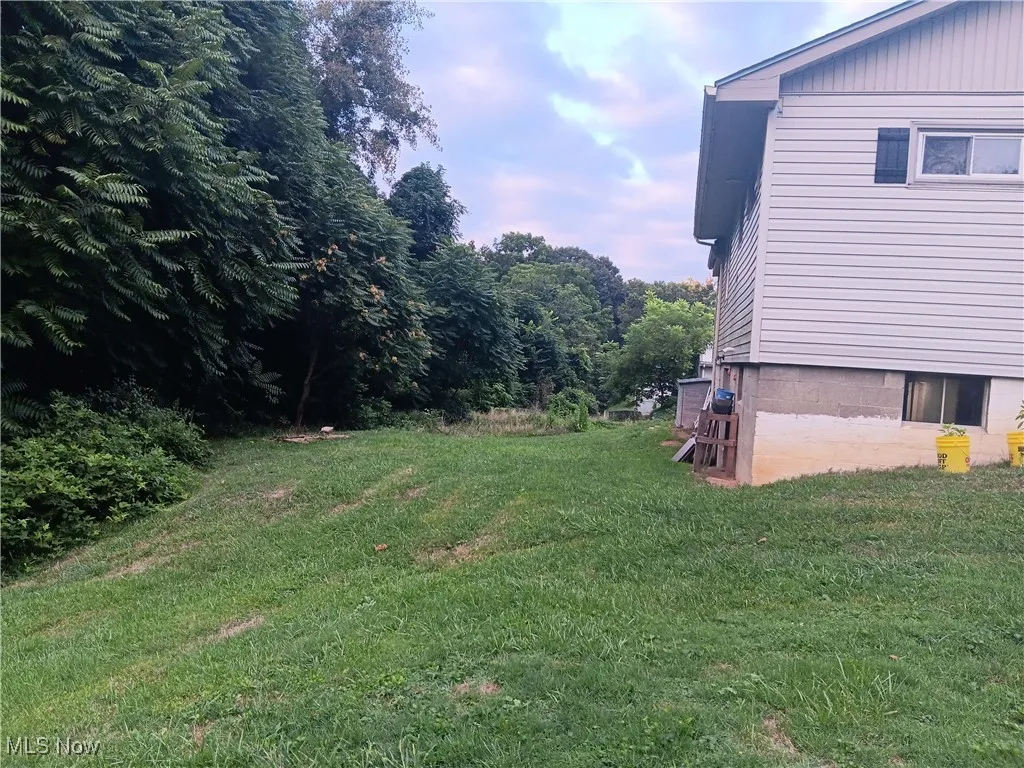 View of green lawn featuring a wooded view