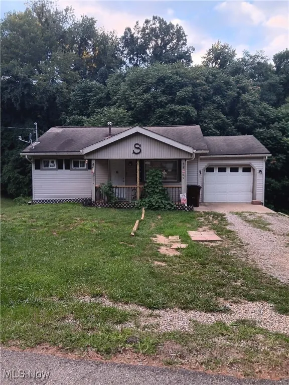 Ranch-style house with driveway, a porch, an attached garage, a front lawn, and roof with shingles
