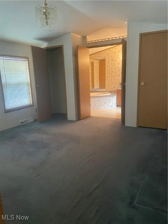 Unfurnished bedroom with wallpapered walls, carpet floors, and a closet