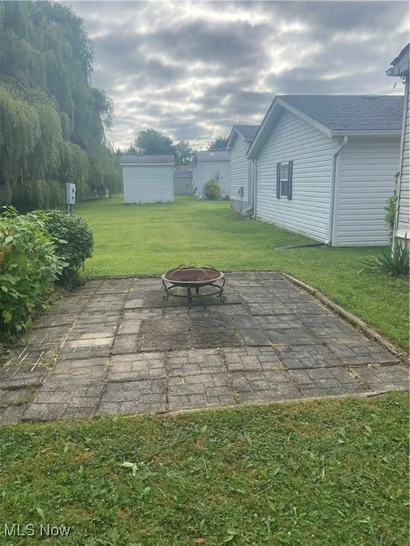 View of patio / terrace with an outdoor fire pit and a storage shed