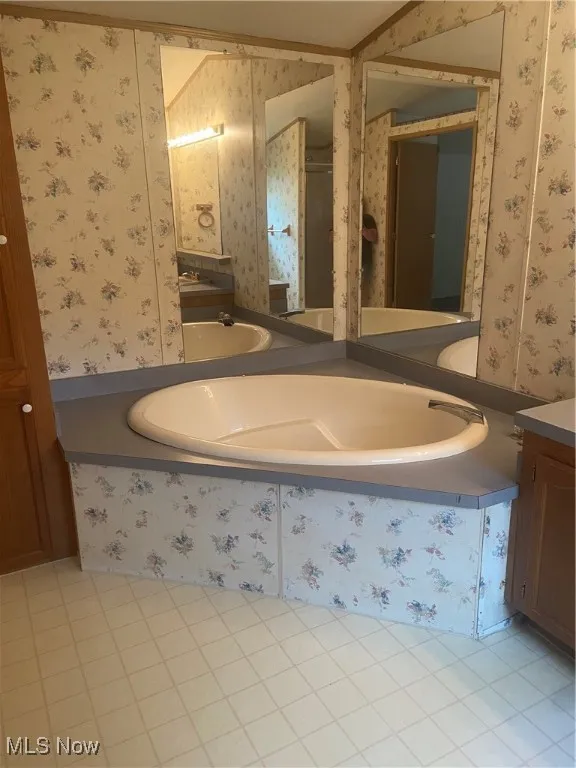 Full bath featuring vanity, wallpapered walls, light tile patterned floors, and a bath