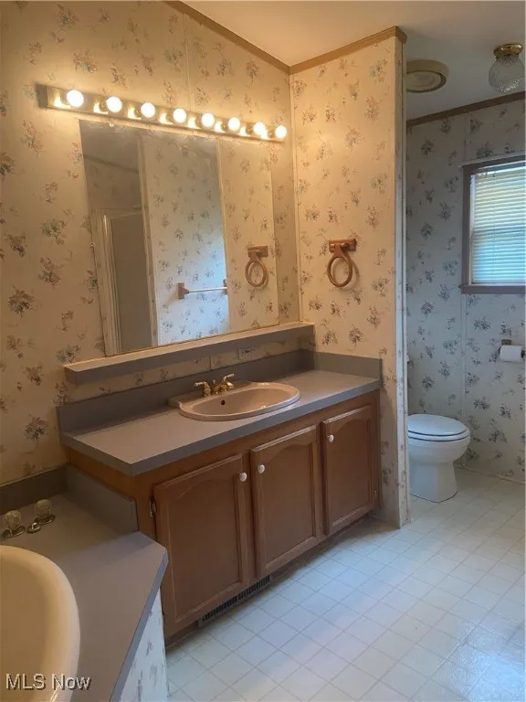 Bathroom featuring wallpapered walls, vanity, a stall shower, ornamental molding, and light tile patterned floors