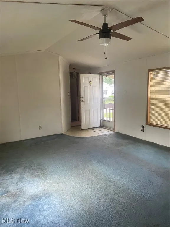 Carpeted spare room with lofted ceiling and a ceiling fan