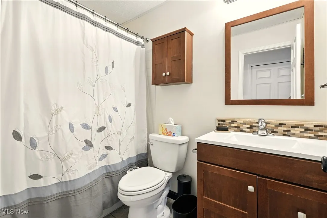 Bathroom featuring vanity, decorative backsplash, and curtained shower